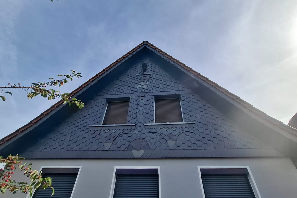 Kunsthandwerkliche Schieferfassade mit dekorativen Schieferornamenten am Hausgiebel